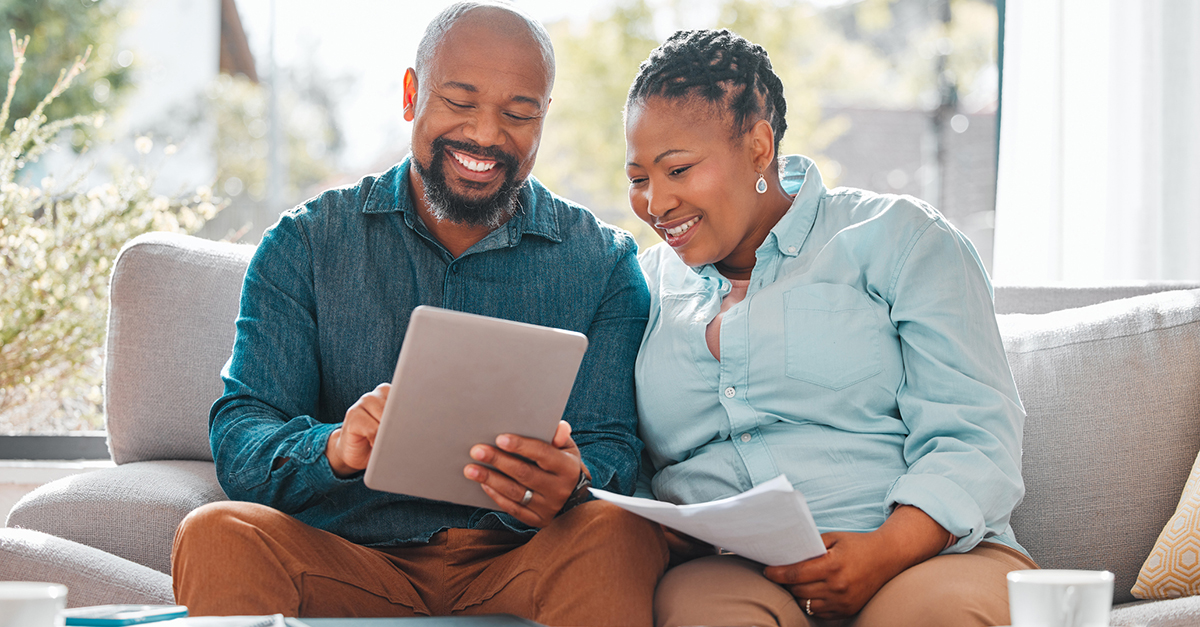 A couple looking at documents on a tablet.